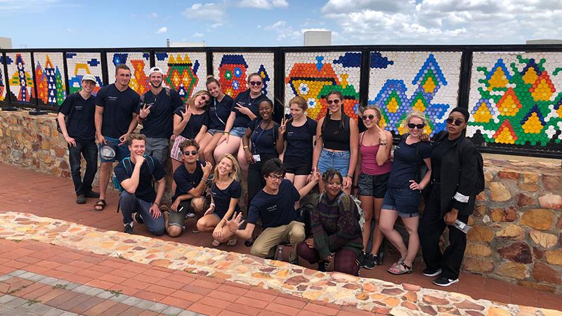 Group photo in front of a mosaic wall